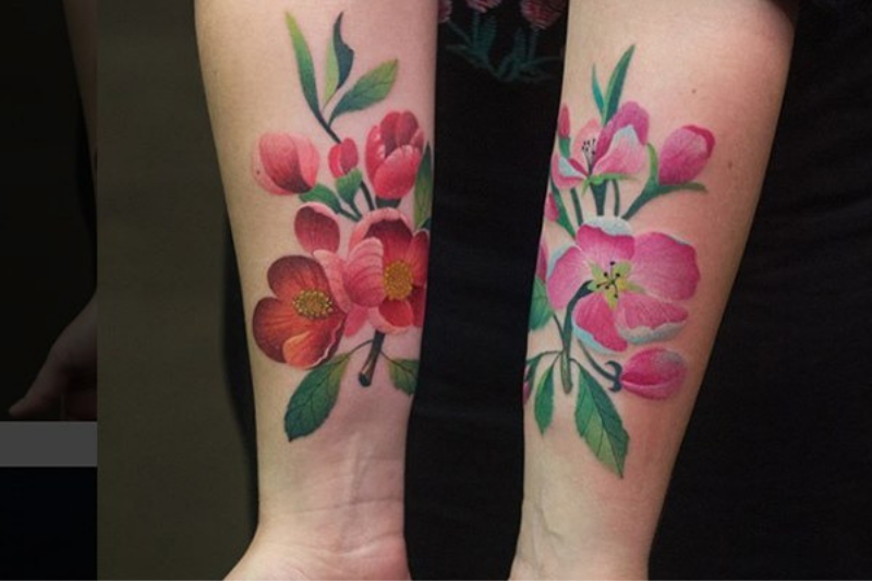 two forearms adorned with pink floral tattoos