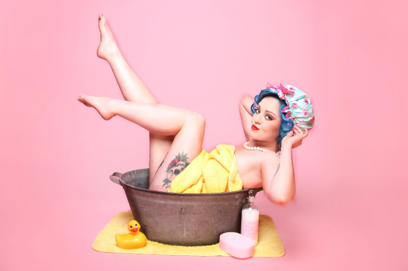 woman in a washing tub with blue hair, wearing a yellow towel