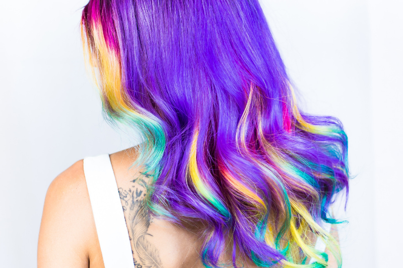 the back of a woman's head, showing her purple hair with rainbow streaks