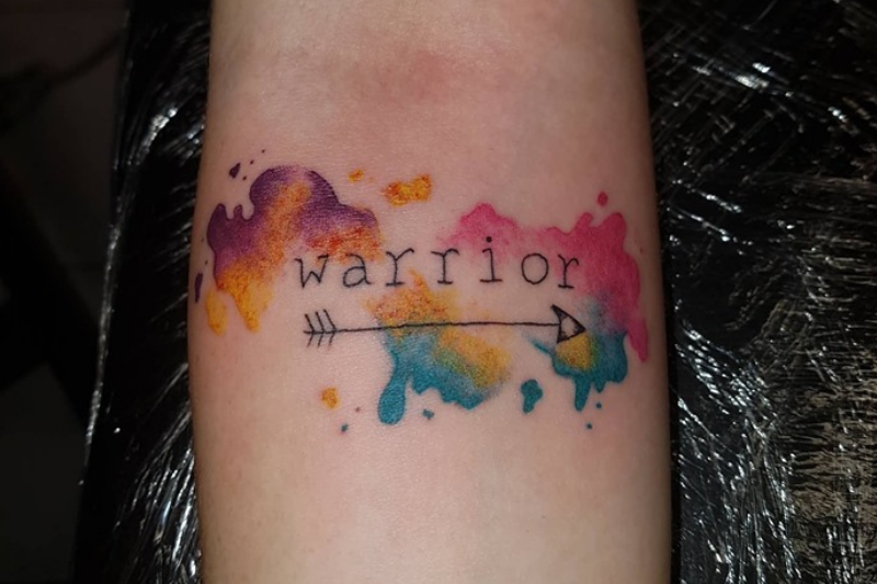 water colour tattoo with the word 'warrior' and an arrow