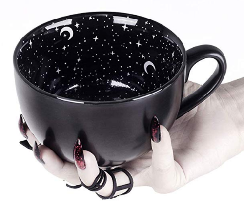 hand holding a large black coffee mug with stars and moons painted on the inside