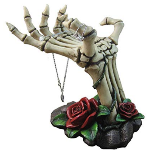 skeleton hand jewelry holder, with red roses at the base around the wrist, holding various jewelry pieces