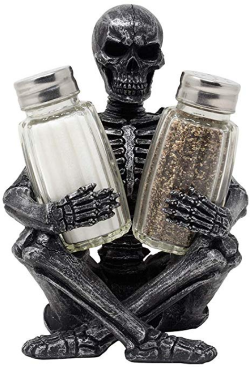 salt and pepper holder shaped like a skeleton sitting with it's legs crossed