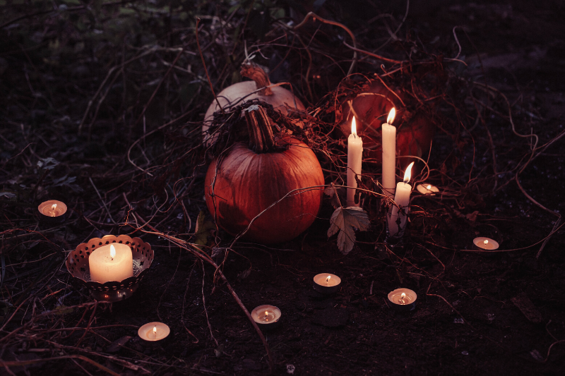pumpkins sitting outside surrounded by candles at night