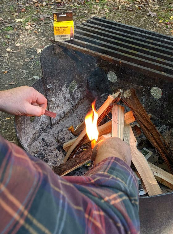 close up of a man lighting a campfire with UCO stormproof sweetfire matches