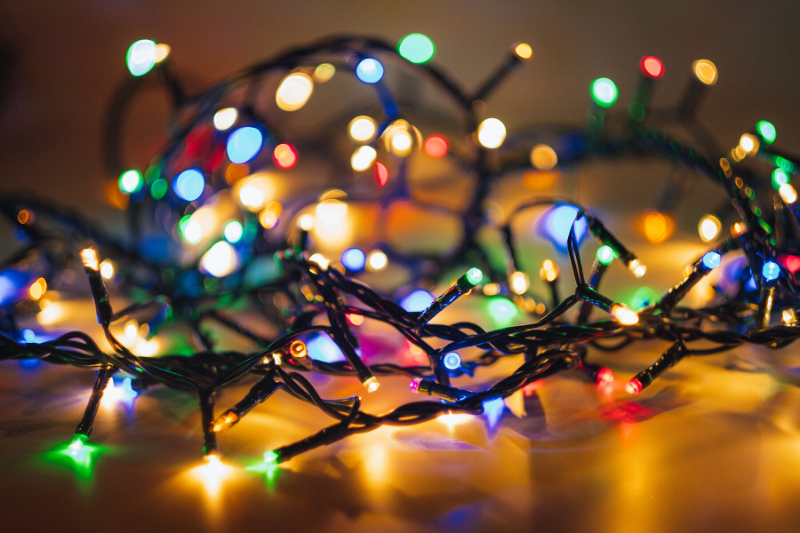 close up of rainbow coloured christmas lights on a wooden floor