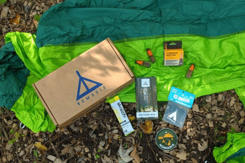nomadik subscription box spread out on the ground among autumn leaves displaying all the products it contains