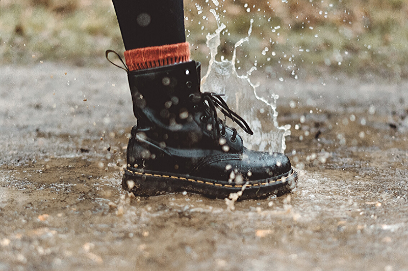 close up of a black combat style boot stepping in a puddle