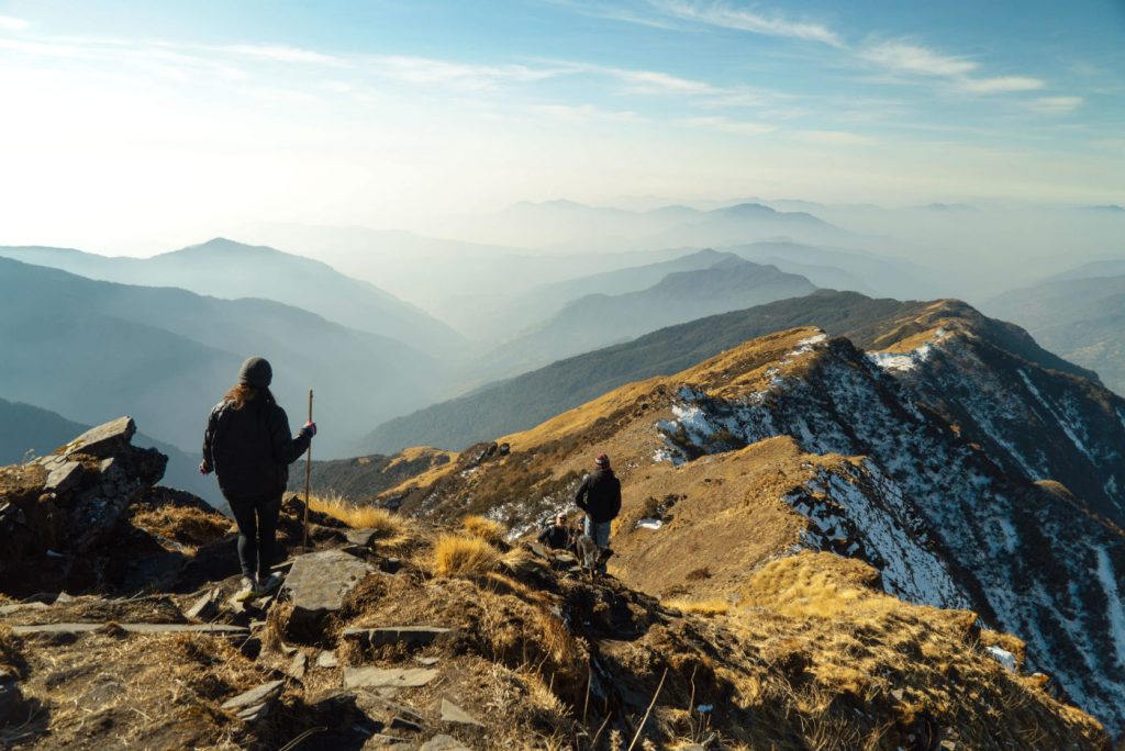 two hikers on a hiking trail in a mountainous region, with a view of mountains in the distance