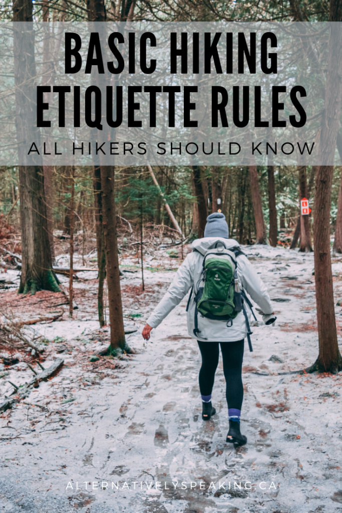 hiker in a white jacket with a green backpack, hiking through a wooded area in the snow with the title basic hiking etiquette rules