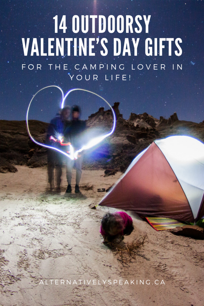 a couple standing at a campsite, next to a maroon and white tent at night, under the stars, making a heart with the light from sparklers with the title 14 outdoorsy Valentine's Day gifts
