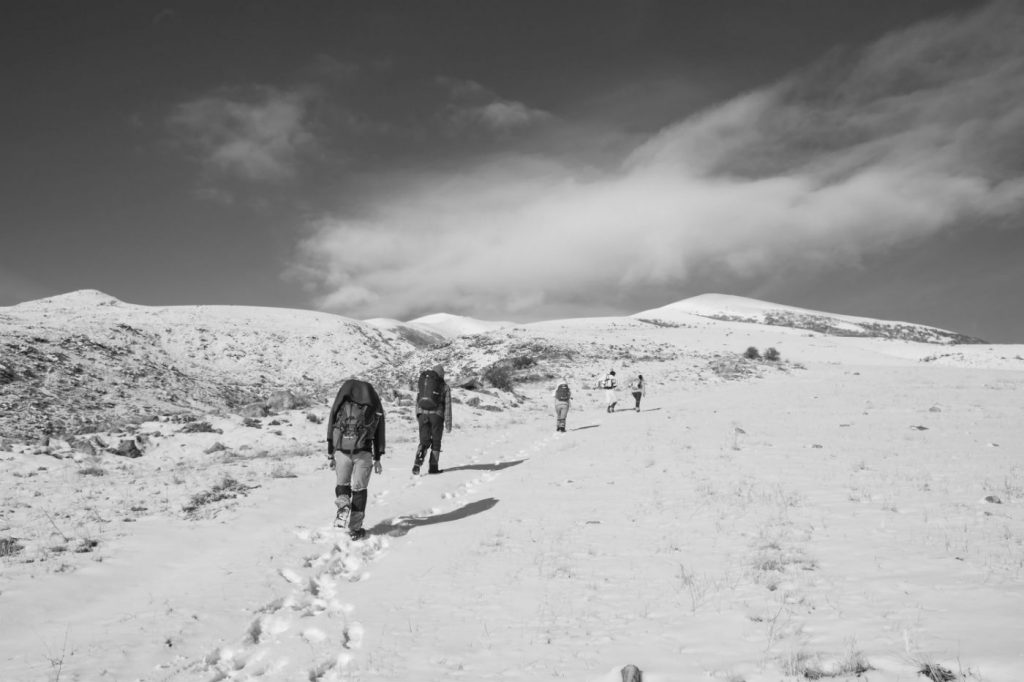 group of hikers making their way through a snow covered area with a grey, cloudy sky
