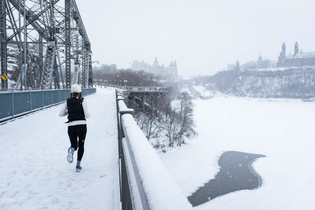 woman running outdoors on a bridge in the winter with snow on the ground