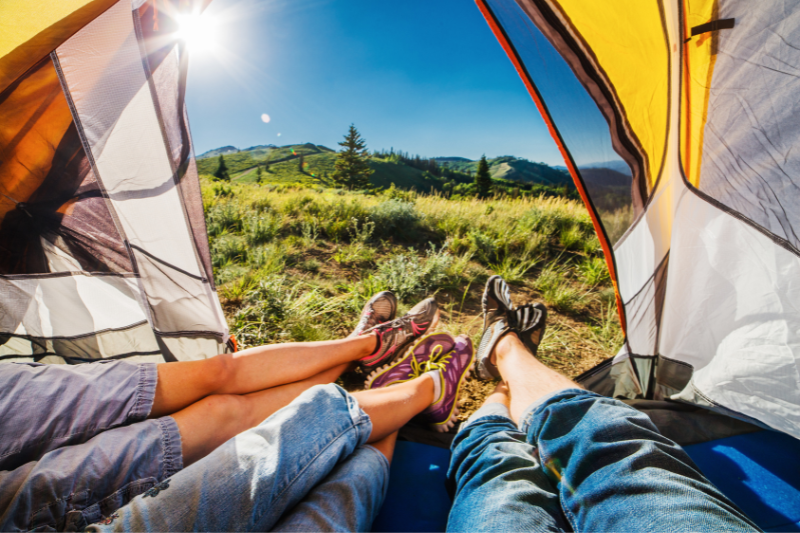 open tent door with people's feet hanging out | The Camping Essentials You’ll Need for Your Next Adventure